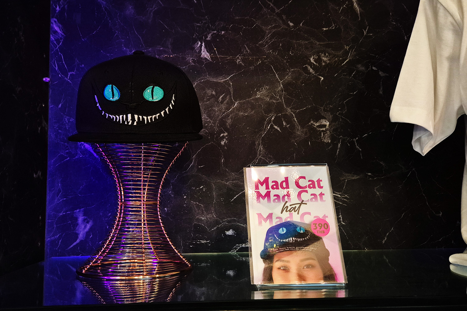 Mad Cat Hat — 390 THB cap with Cheshire Cat eyes and fangs embroidered on black base