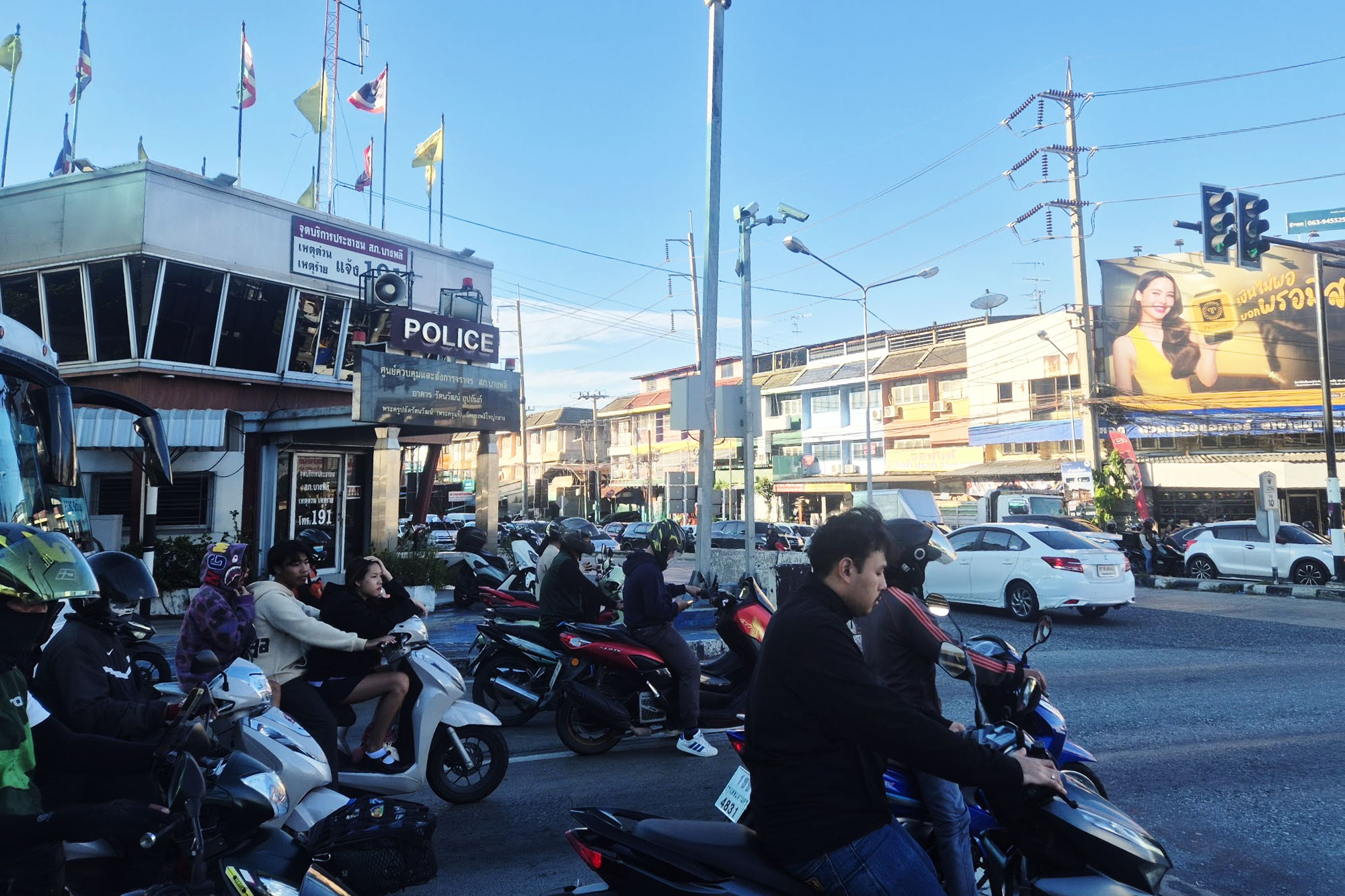A motorbike carrying three riders without helmets on a Bangkok road